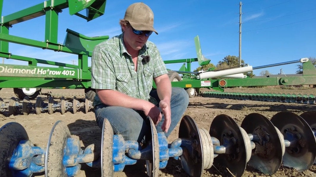 farmer inspecting surface tillage equipment